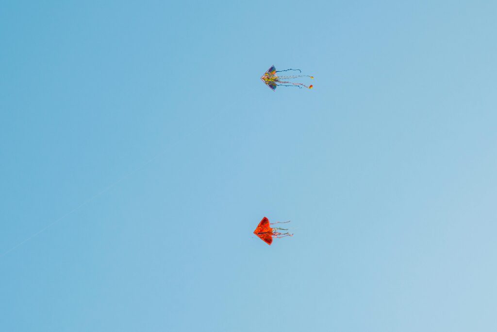 Sobre el universo Kite Wars Two vibrant kites soaring in the clear blue sky of Quy Nhơn, Vietnam.