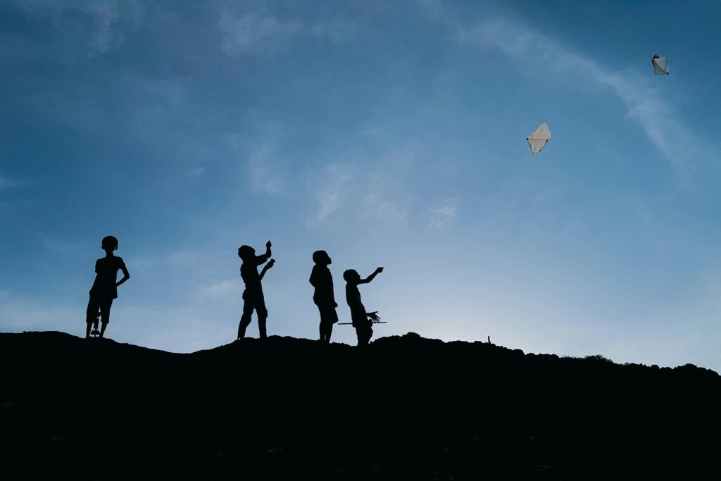 Sobre el universo Kite Wars Silhouettes of children flying kites against evening sky in Chattogram, Bangladesh. A picturesque and playful scene.